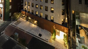 Un hotel de varios pisos con un diseño moderno, que presenta un patio central con zonas de estar y una escalera que conduce a los pisos superiores.