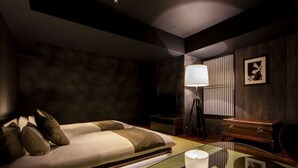 Un dormitorio moderno con cama, mesita de noche, lámpara y una mesa de centro de vidrio.