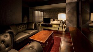 Una sala de estar moderna con un sofá de cuero, una mesa de centro de madera, un televisor sobre un mueble bajo y una lámpara de pie.