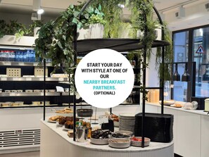 A breakfast buffet area with various food items and a circular sign promoting nearby breakfast partners.