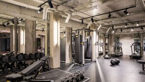 Un gimnasio con equipo de levantamiento de pesas, cintas de correr y un espejo grande.