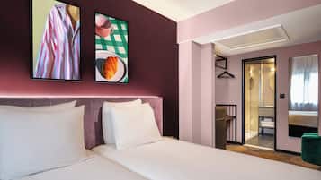 A hotel room with a large bed, a bedside table, a mirror, and a door leading to a bathroom.