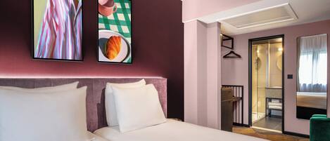 A hotel room with a large bed, a bedside table, a mirror, and a door leading to a bathroom.