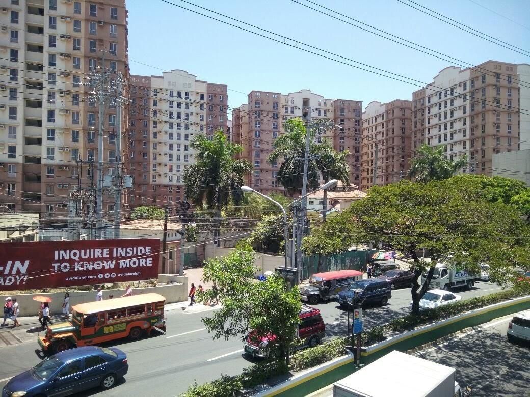 A busy urban street with multi-story residential buildings, a bus, and cars.