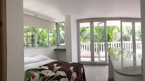 Une chambre à coucher avec un lit, une fenêtre et un balcon donnant sur un paysage verdoyant.