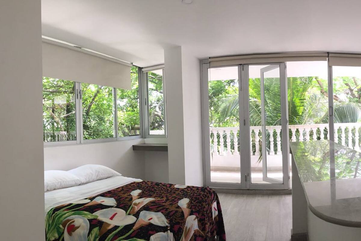 Une chambre à coucher avec un lit, une fenêtre et un balcon donnant sur un paysage verdoyant.