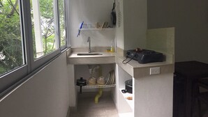 Une petite salle de bain étroite, avec une fenêtre, un lavabo et une étagère contenant des articles de toilette.
