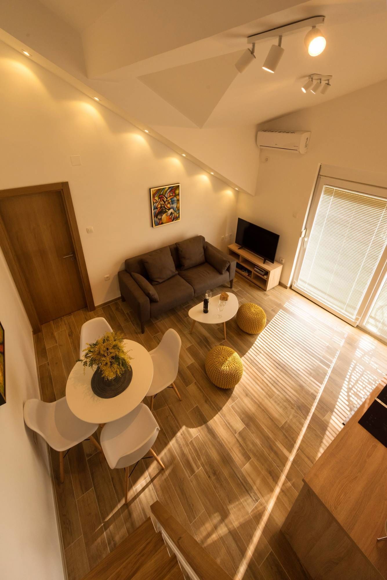 Una sala de estar moderna con sofá, televisión y comedor con sillas y una mesa.