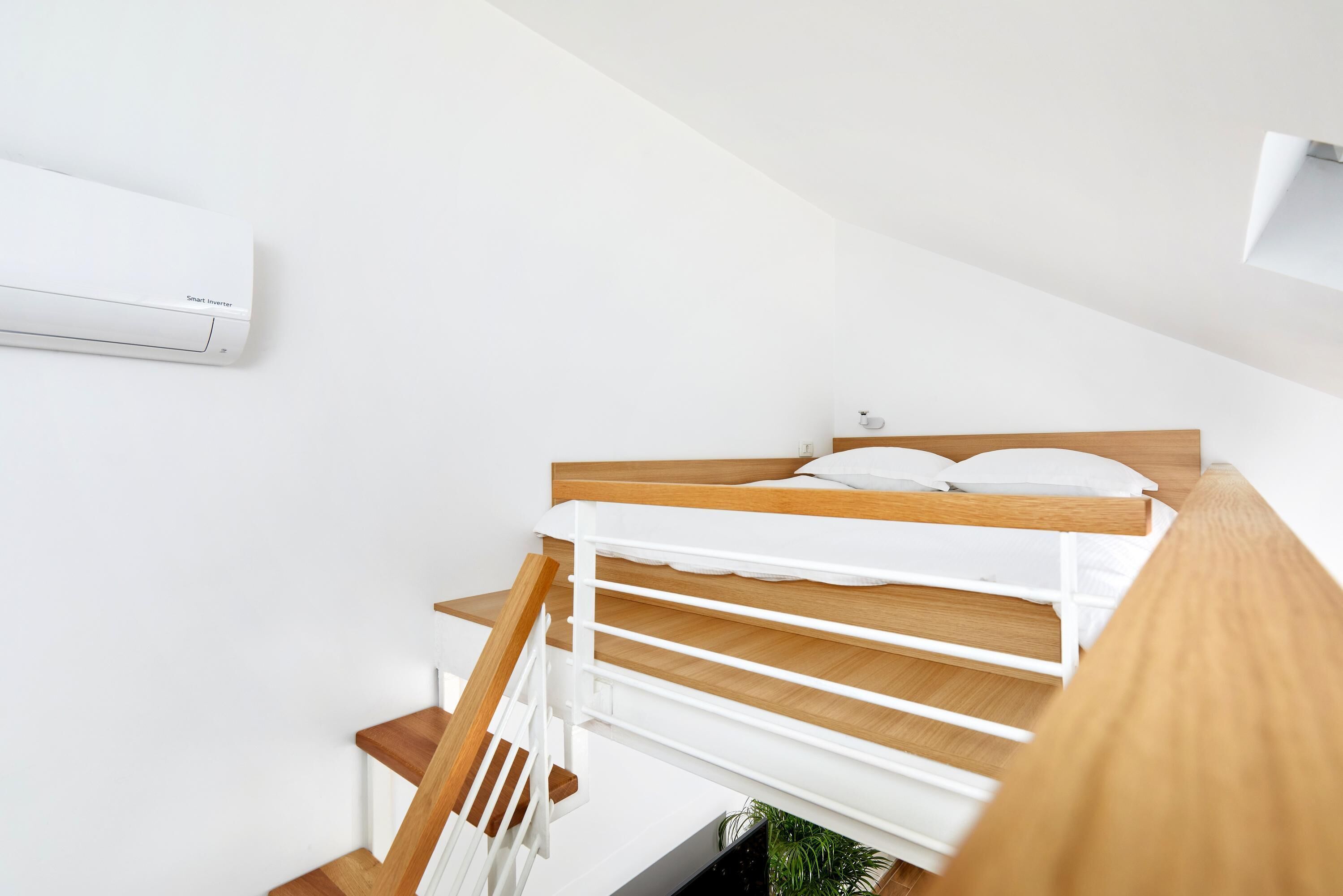 A modern bedroom with a bunk bed, white walls, and a wooden floor.