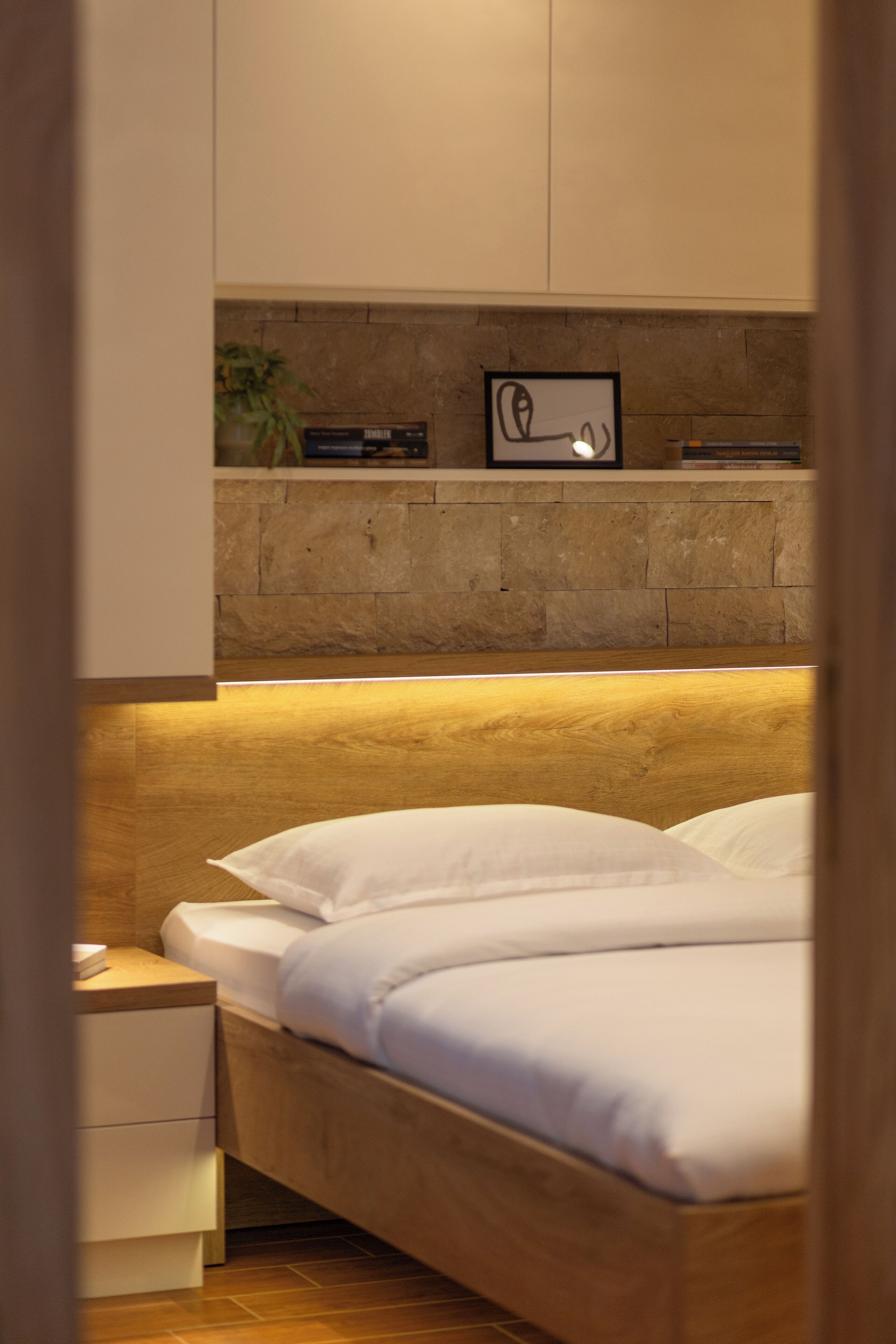 A bedroom with a wooden headboard, a bedside table, and a nightstand.