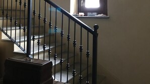 A staircase with a black balustrade leading to a landing. A small window with a view of the outdoors is visible on the landing wall. - B&B Cascina Garaita (Genola)