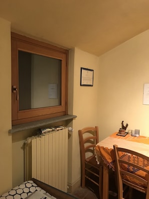 Un pequeño comedor con una mesa, sillas, un ventanal y un certificado enmarcado en la pared.