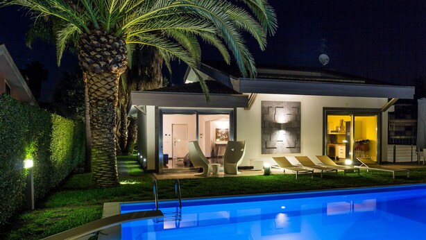 Une maison moderne dotée d’une piscine, d’un espace extérieur aménagé et d’une entrée bien éclairée.
