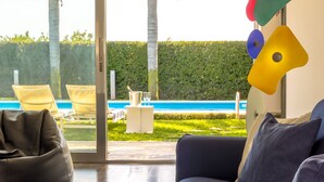 Un salon moderne avec vue sur une piscine et une pelouse bien entretenue.