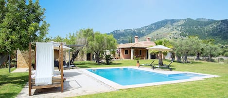 Une piscine avec une terrasse en bois, un auvent et un lit à baldaquin.
