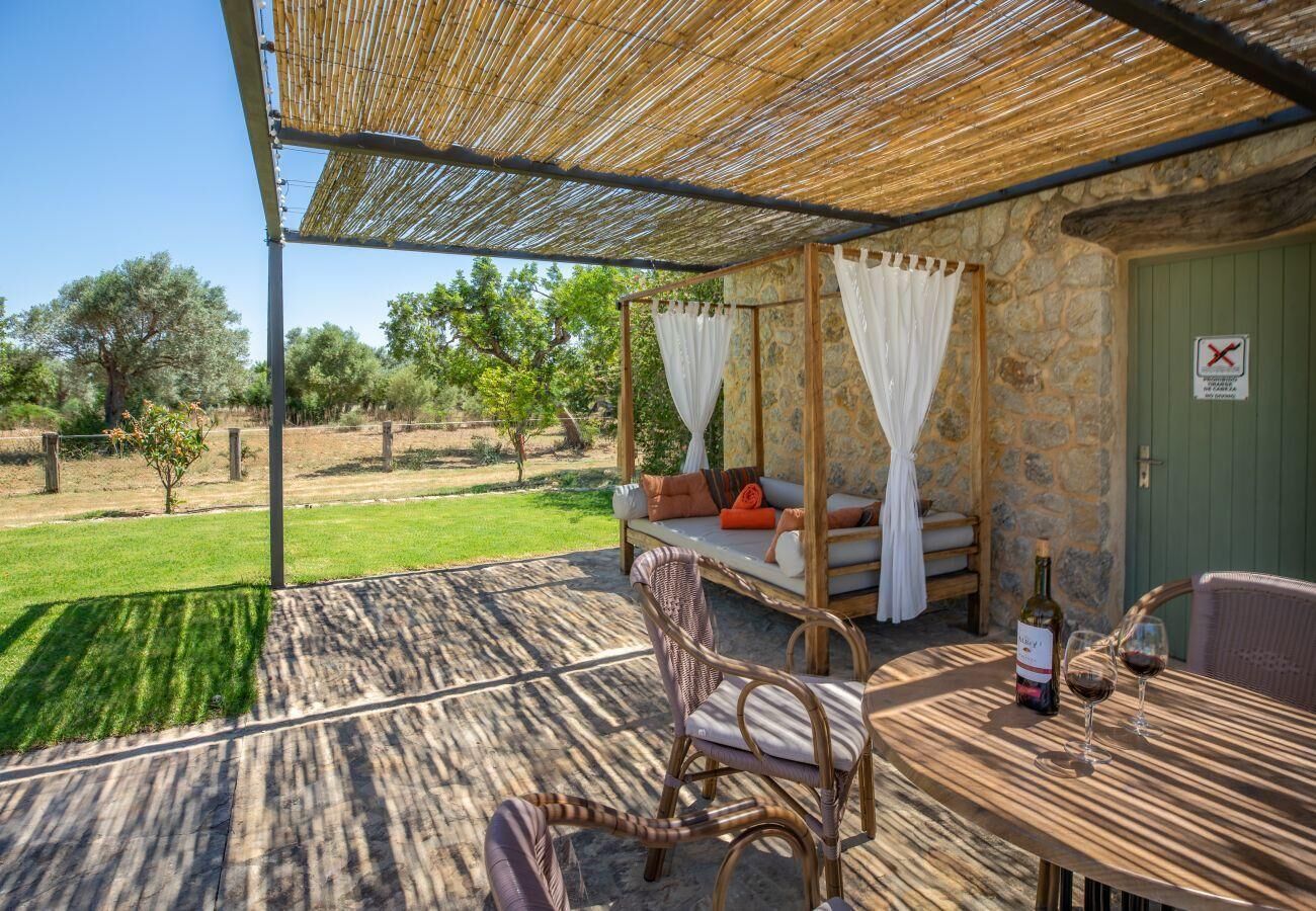 Ein Sitzbereich im Freien mit Tisch, Stühlen und einer Couch unter einer beschatteten Pergola.