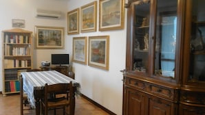 A dining area with a table set for two, a bookshelf, a television, and a cabinet with glass doors. - B&B Al Calypso (Curtatone)