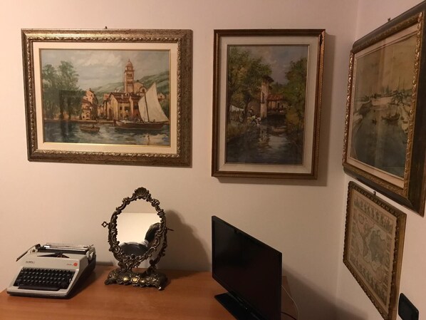 A room with a desk, a typewriter, a mirror, and three framed paintings on the wall. - B&B Al Calypso (Curtatone)