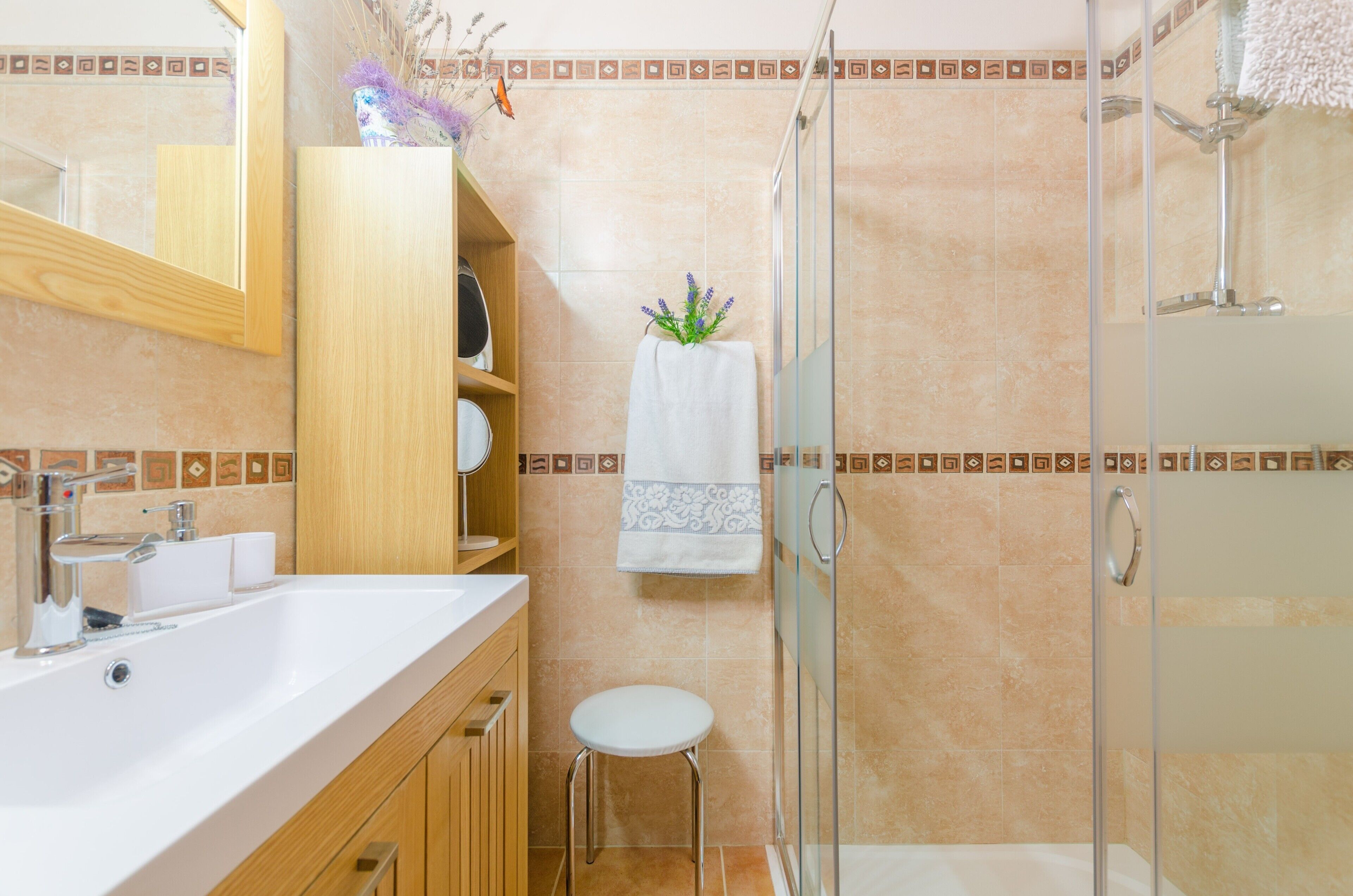 Un baño con ducha, lavamanos y espejo.