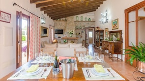 A dining area with a wooden table set for a meal, a chandelier, and a stone fireplace. - ES MOYÀ DES PINS - Villa with private pool in Muro. Free WiFi (Muro)