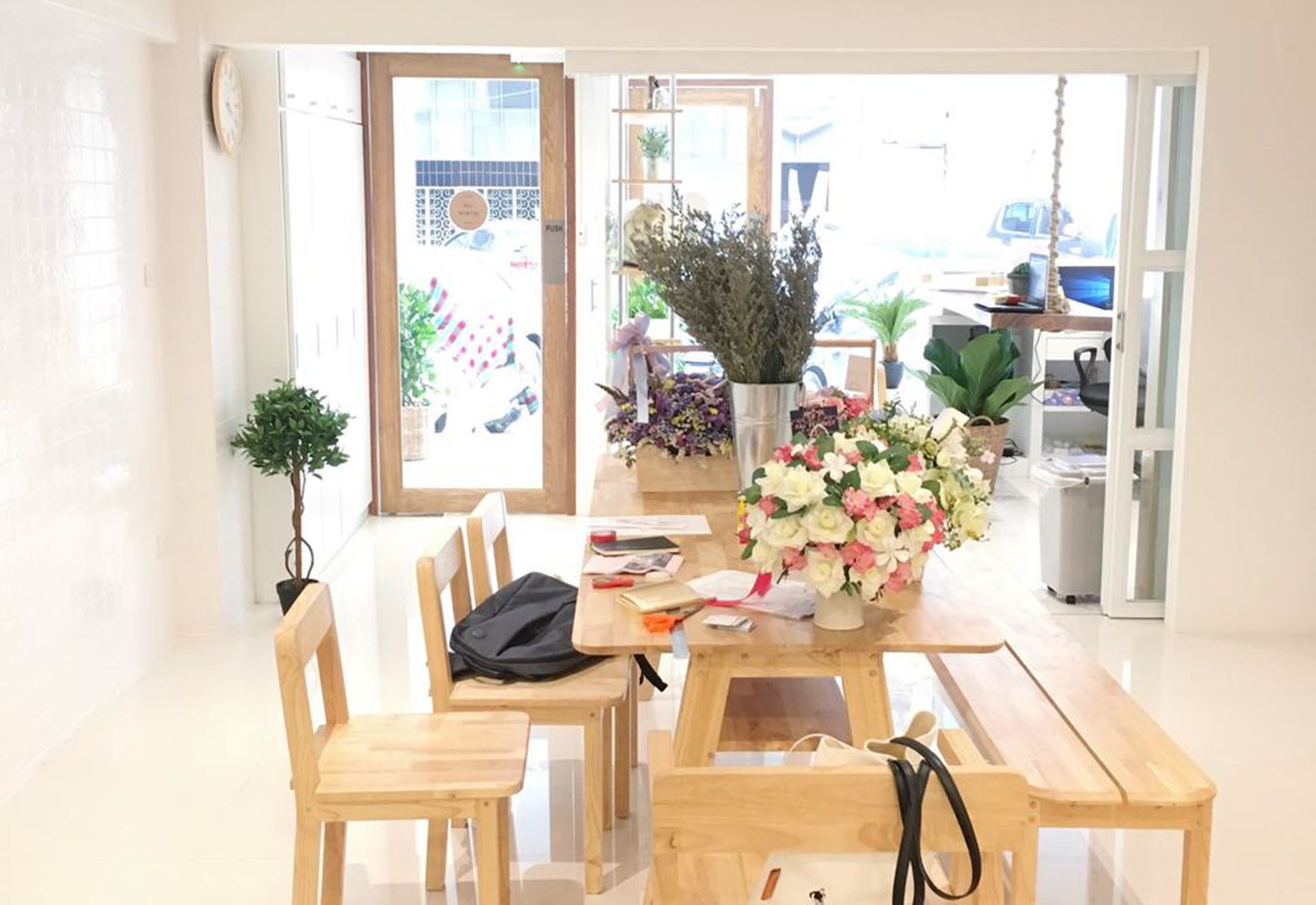 A bright, modern room with a wooden table and chairs, a vase of flowers, and a potted plant.