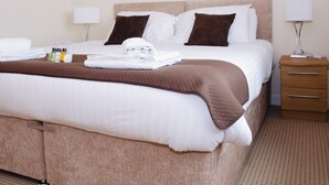 A neatly made bed with a brown blanket, white pillows, and a set of toiletries on the side. - Elforma - Tudsbery House (Edinburgh)