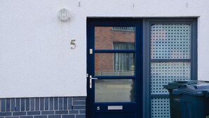 A dark blue door with a glass panel, a number '5' on the wall, and a trash bin next to it. - Elforma - Tudsbery House (Edinburgh)
