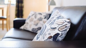 A black leather sofa with patterned cushions. - Elforma - Tudsbery House (Edinburgh)