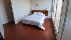 A bedroom with a bed, a nightstand, a wall-mounted lamp, and a door. - 2-room apartment, sleeps 5 with balcony - Saint-Jean-de-Monts (Saint-Jean-de-Monts)