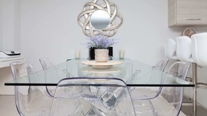 A modern dining area with a glass table, clear chairs, and a decorative wall piece. - Luxurious Central Edinburgh Apartment - Sleeps 6 (Edinburgh)