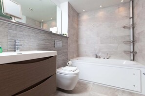 Une salle de bain moderne avec un lavabo, des toilettes et une baignoire, le tout de couleur blanche.