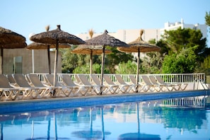 A swimming pool with lounge chairs and thatched umbrellas.