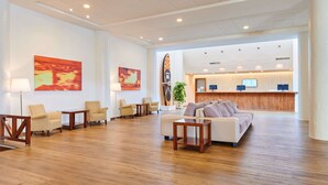 A spacious lobby with a reception desk, seating area, and artwork on the walls. -    AluaSun Cala Antena – All Inclusive (Manacor)