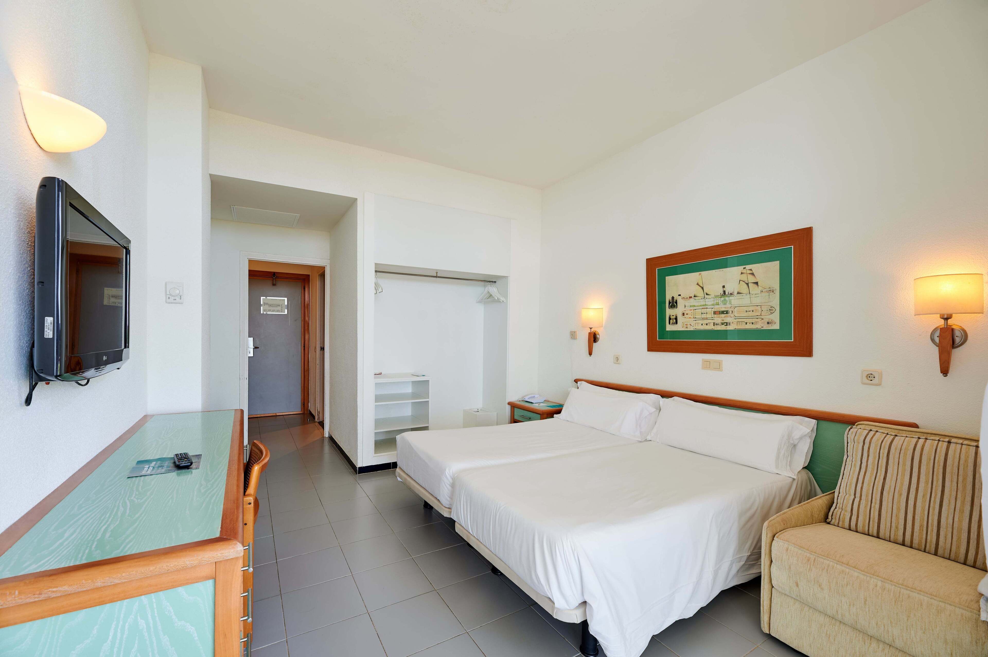 A hotel room with two beds, a TV, a desk, and a couch.