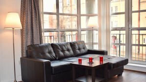 A black leather sofa with a wooden coffee table, two red candles, and a floor lamp.