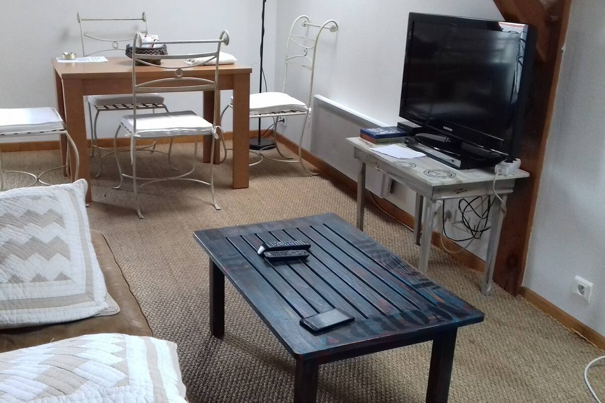 A room with a bed, a wooden table, a TV, and a chair.