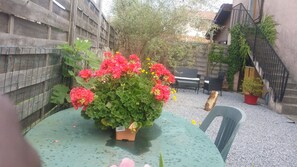 A green table with a potted plant in the center, surrounded by a wooden fence and a staircase. - Le Petit Bonheur Biscarrosse (Biscarrosse)