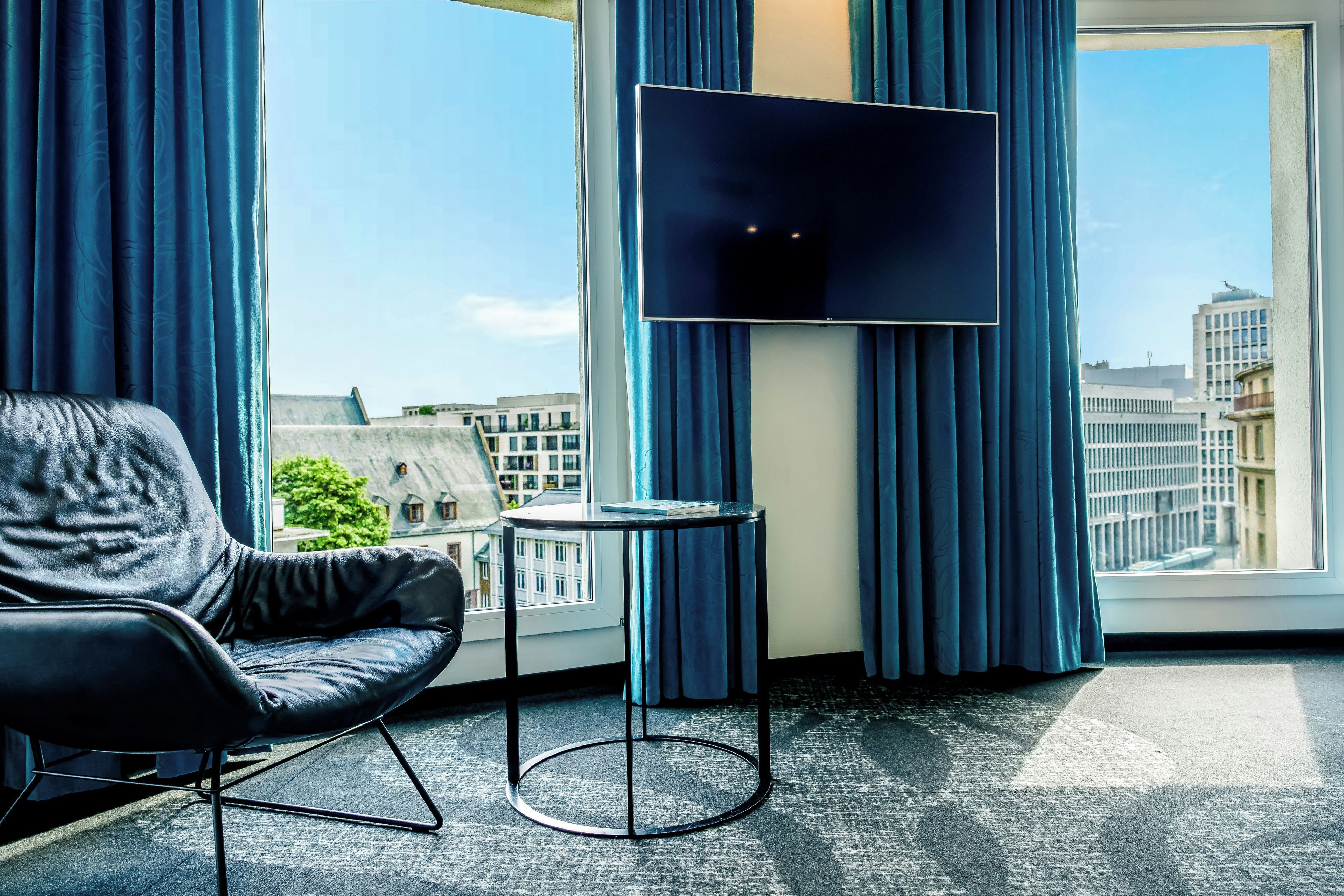 A modern hotel room with a leather chair, a small table, and a flat-screen TV.