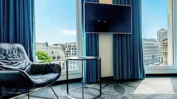 Una habitación de hotel moderna con un sillón de cuero, una mesita pequeña y un televisor de pantalla plana.