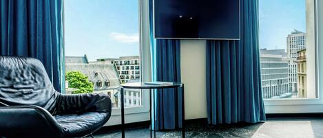 A modern hotel room with a leather chair, a small table, and a flat-screen TV.