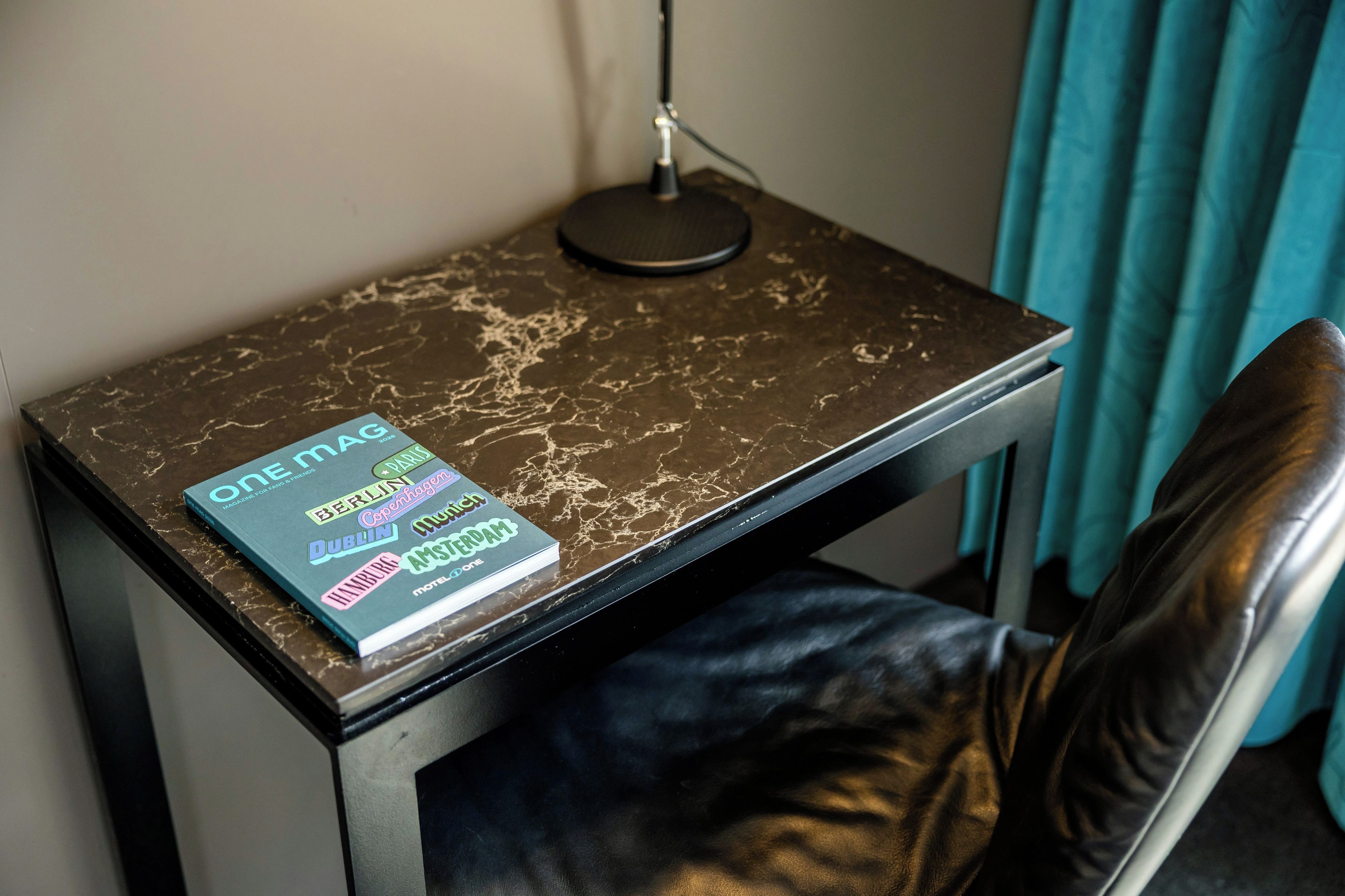 A small table with a book titled 'One Magazine' and a lamp.