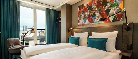 A hotel room with a large bed, a desk, a chair, and a window with curtains.