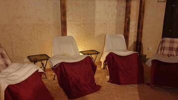 Two comfortable chairs sit against a textured wall, accompanied by a small table with a wooden door visible in the background.