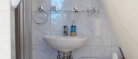 A bathroom with a white sink, a mirror, a towel rack, and a small heater unit.
