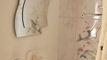 Un baño con secador de pelo montado en la pared, un perchero y un espejo decorativo.