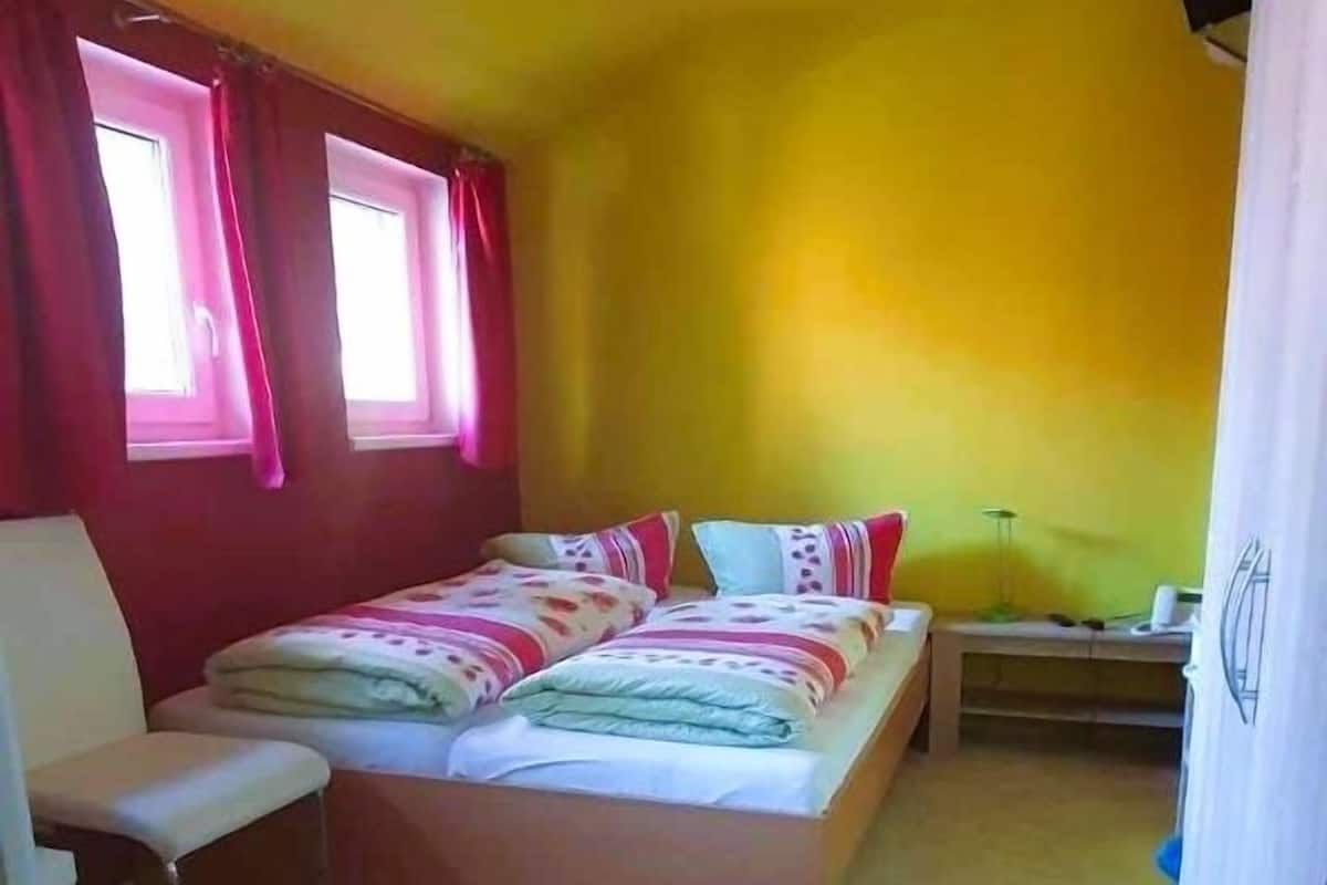 Une petite pièce lumineuse, avec un lit, une chaise et un bureau.