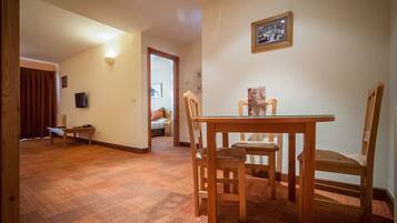 A dining area with a wooden table and chairs, a framed picture on the wall, and a carpeted floor.
