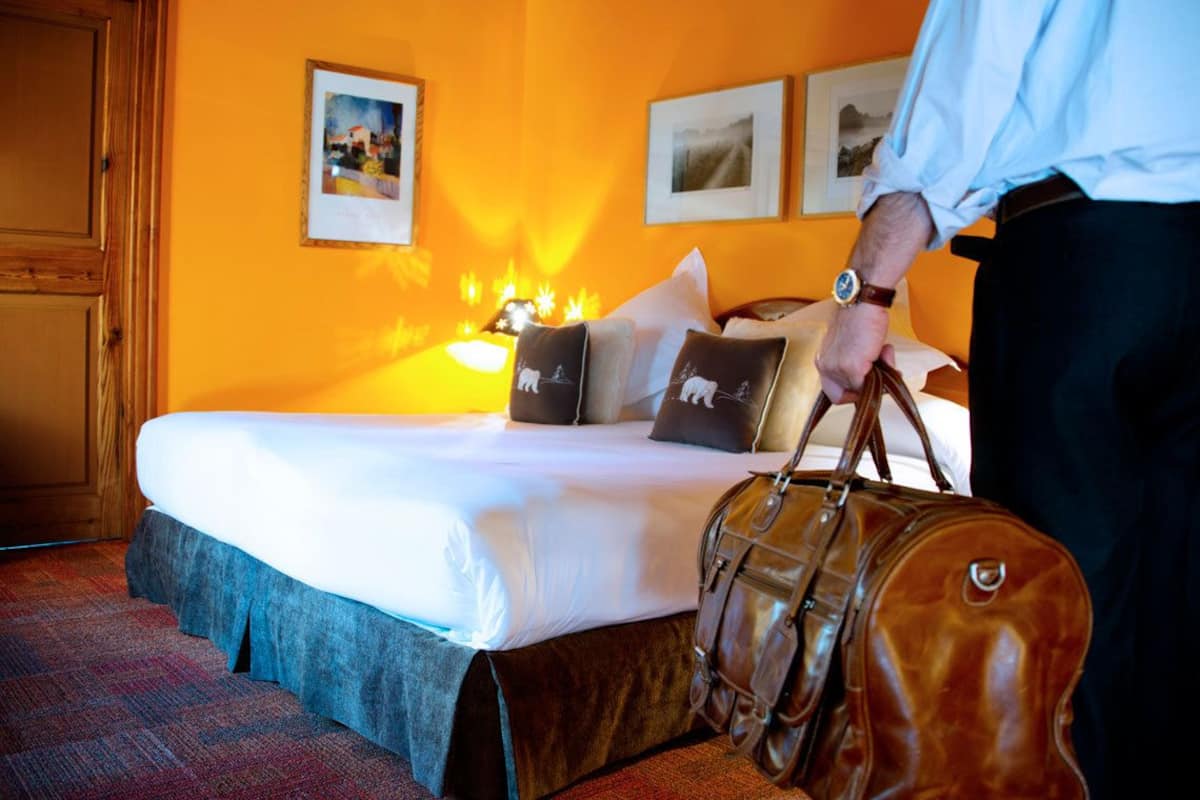 Ein Hotelzimmer mit einem Bett, Kissen, einer Lampe und einem Holzschrank.
