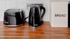 Eine Küche mit Toaster, Wasserkocher und Aufbewahrungsbehältern, beschriftet mit Kekse, Kaffee, Tee und Zucker.