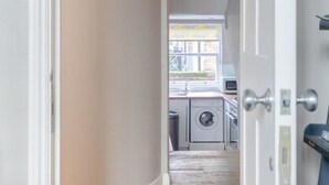 Ein Flur, der zu einer Küche mit Fenster, Waschmaschine und Spüle führt.